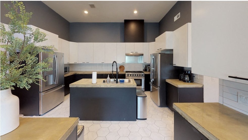 a large kitchen with black counters and stainless steel appliances