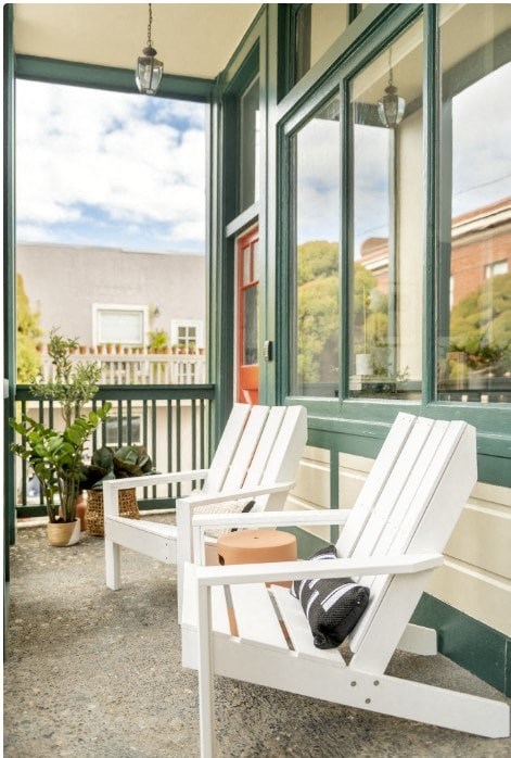a porch with two chairs and a table and large windows