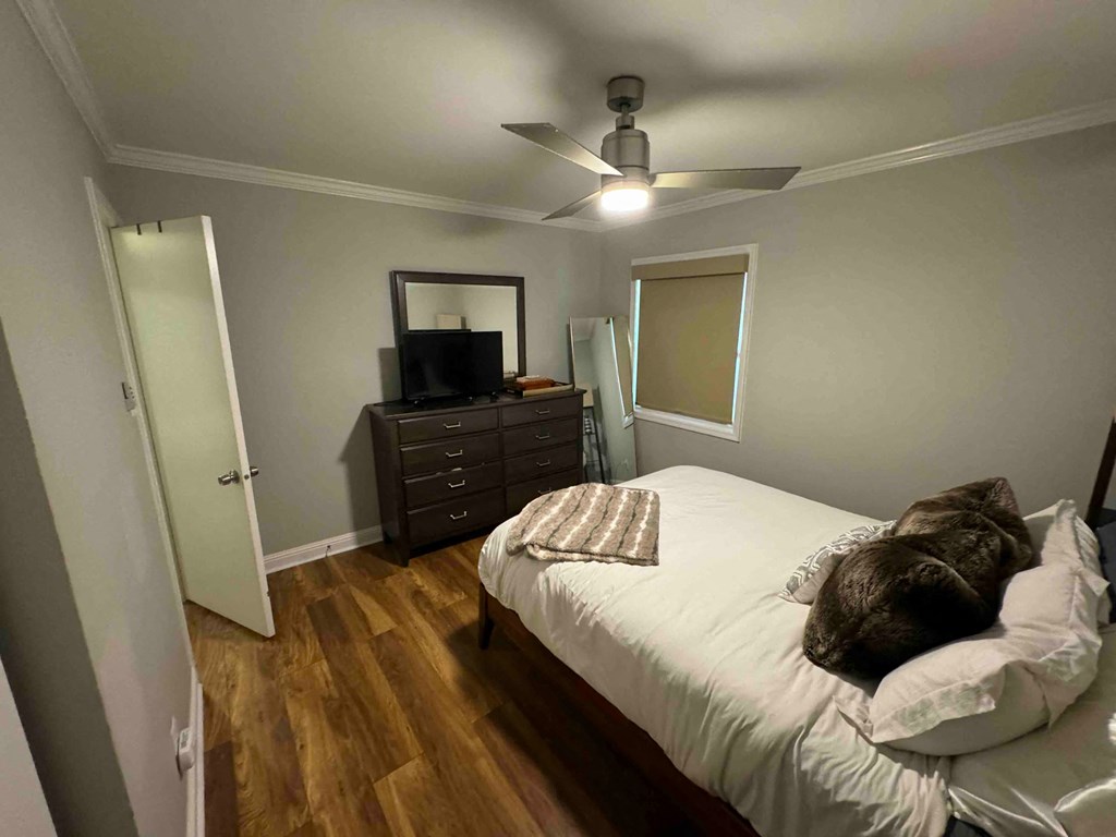 a bedroom with a bed and a ceiling fan and a dresser