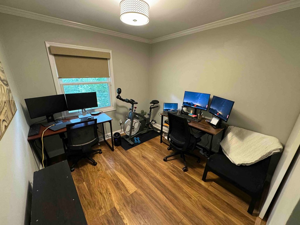 a home office with two computers and a bike in the corner