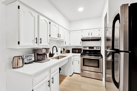 a white kitchen with stainless steel appliances and white cabinets