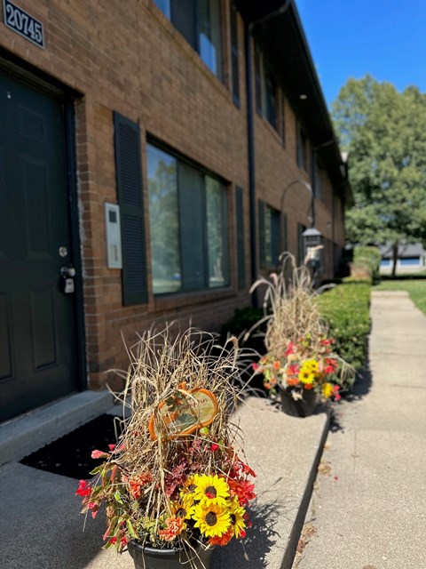 the front of a building with potted flowers on the sidewalk