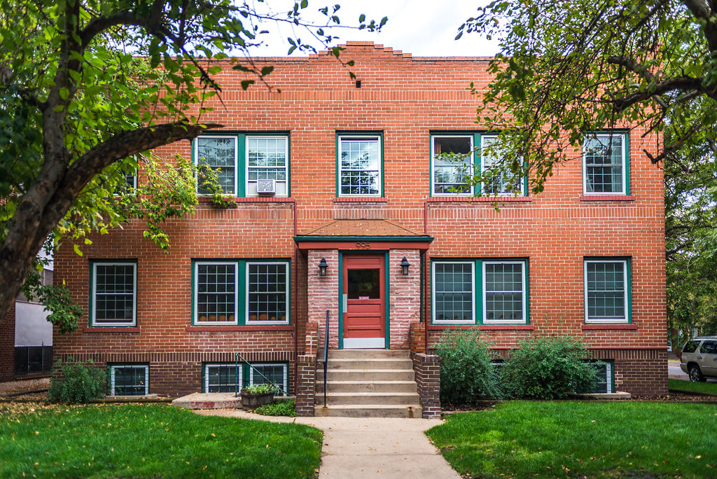 a red brick building with a red door and green windows