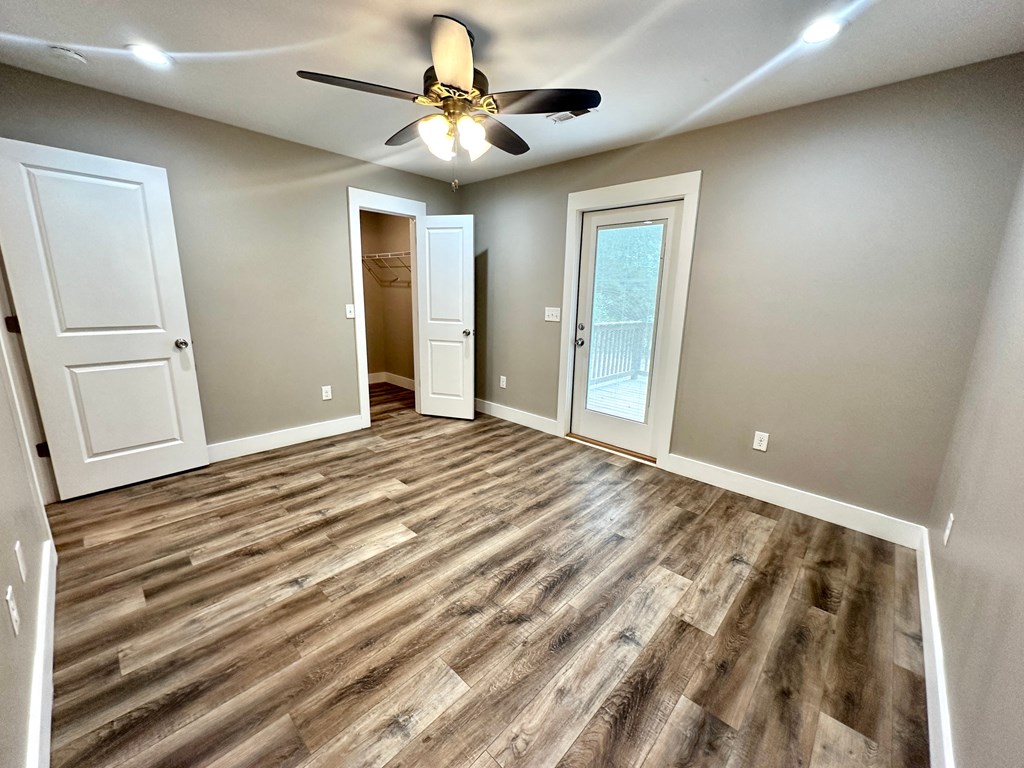 an empty living room with wood floors and a ceiling fan