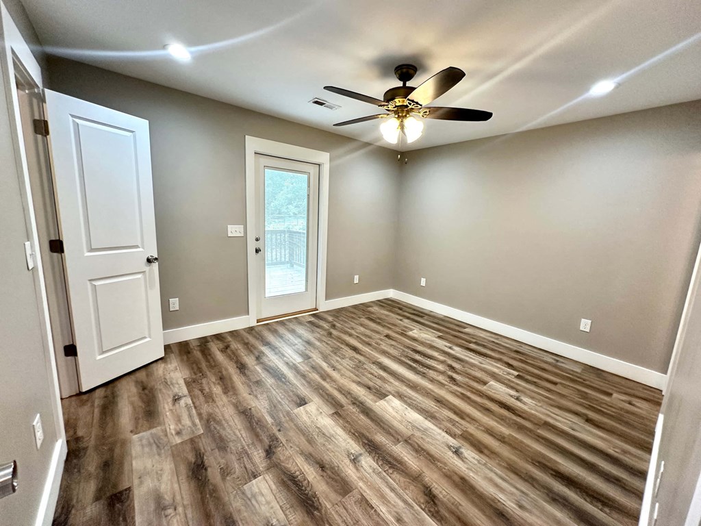 an empty living room with a ceiling fan and a door