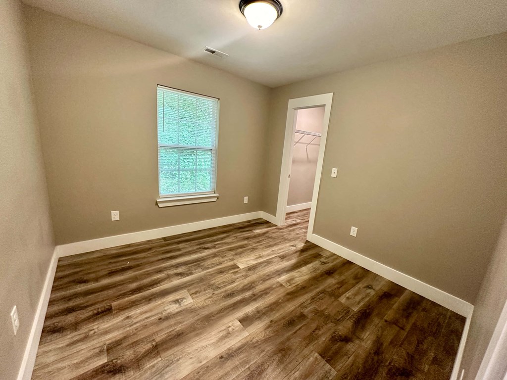 a empty living room with hard wood floors and a window