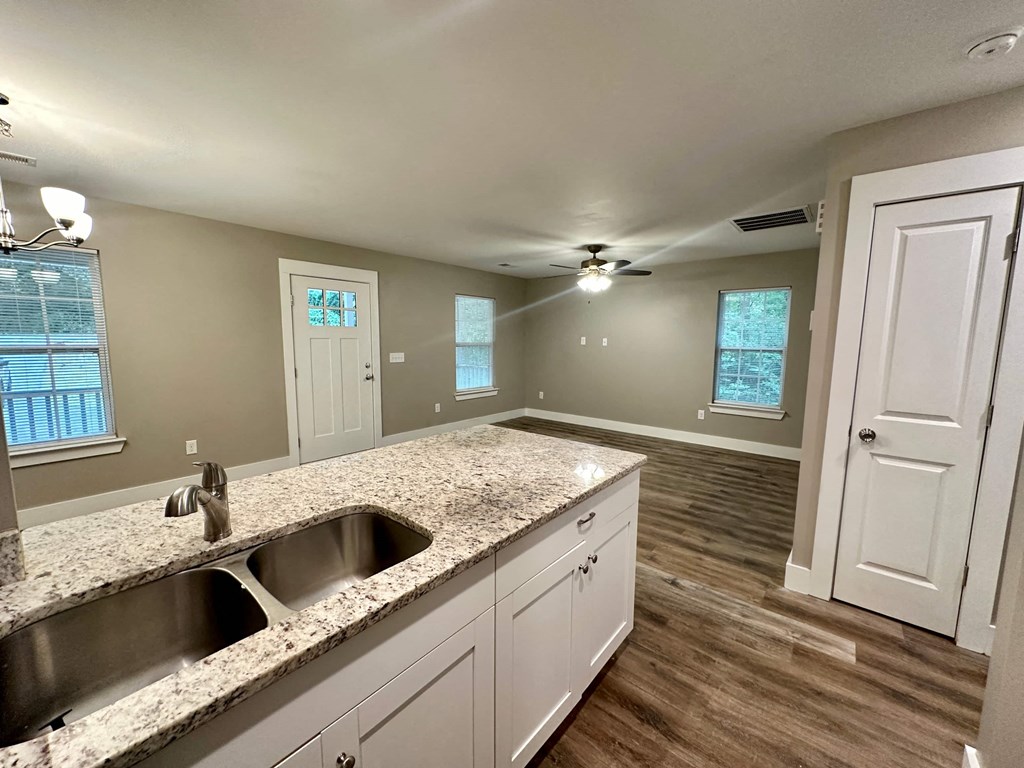 the kitchen and living room of a house with white cabinets