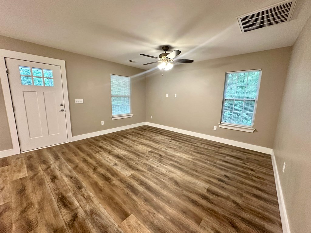 an empty living room with a ceiling fan and a door