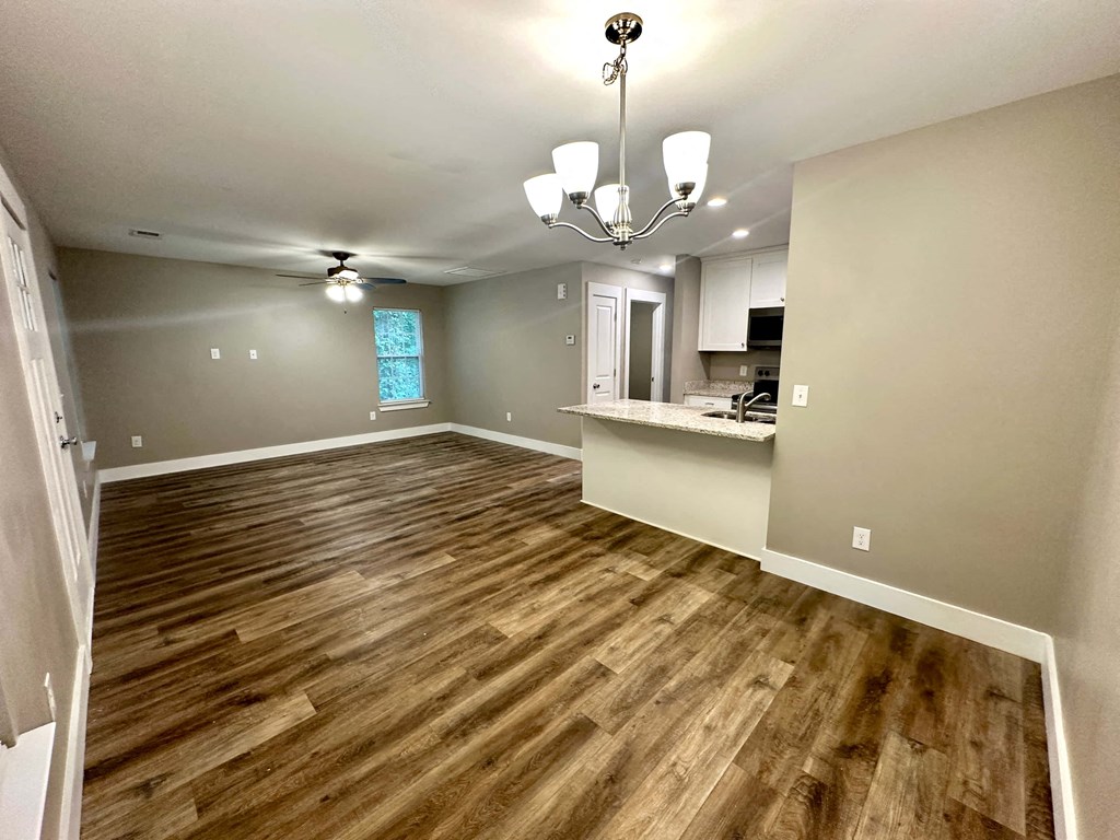an empty living room and kitchen with wood flooring