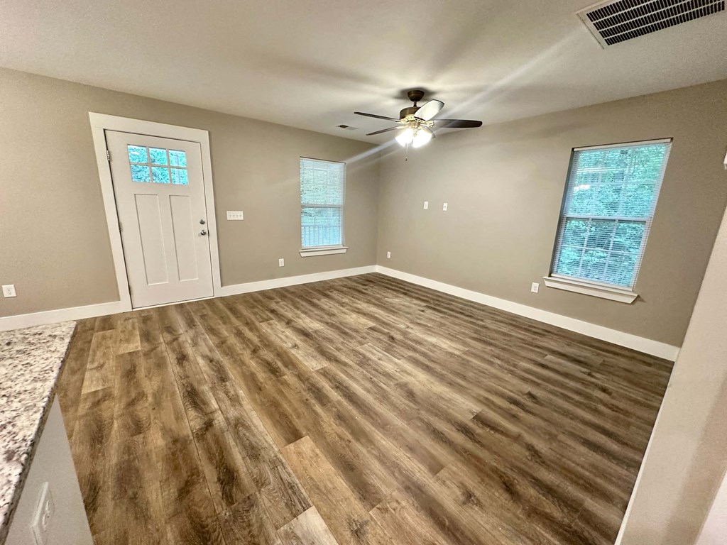 an empty living room with hardwood floors and a ceiling fan