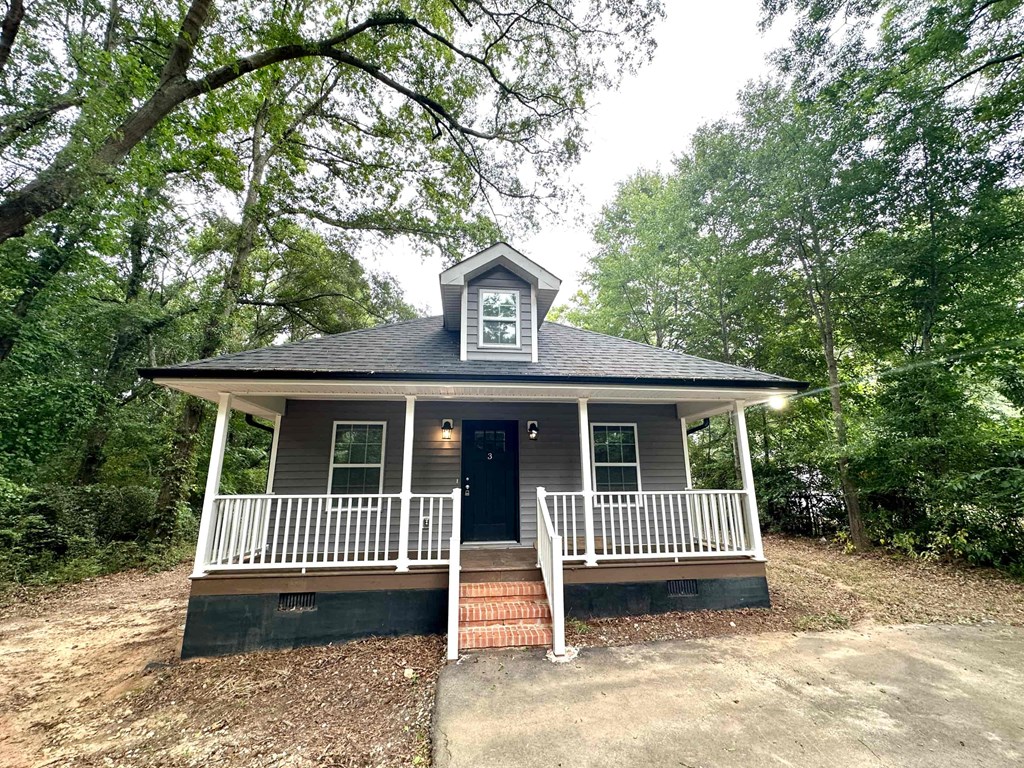 a small house with a porch surrounded by trees