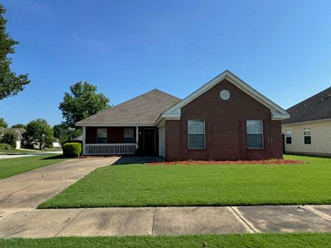 a brick house with a lawn and a driveway