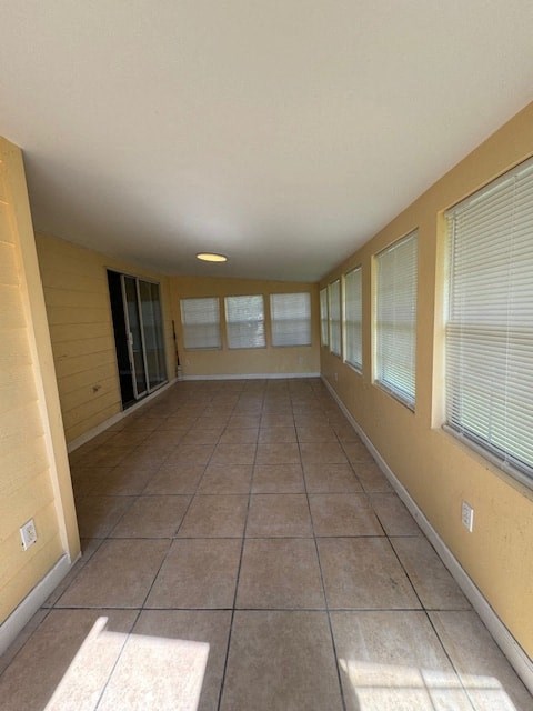 a long empty room with windows and a tile floor