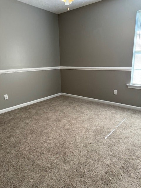 an empty room with a carpeted floor and two windows