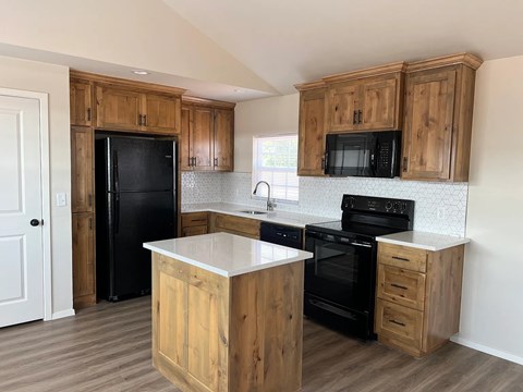 A kitchen with wooden cabinets and black appliances.
