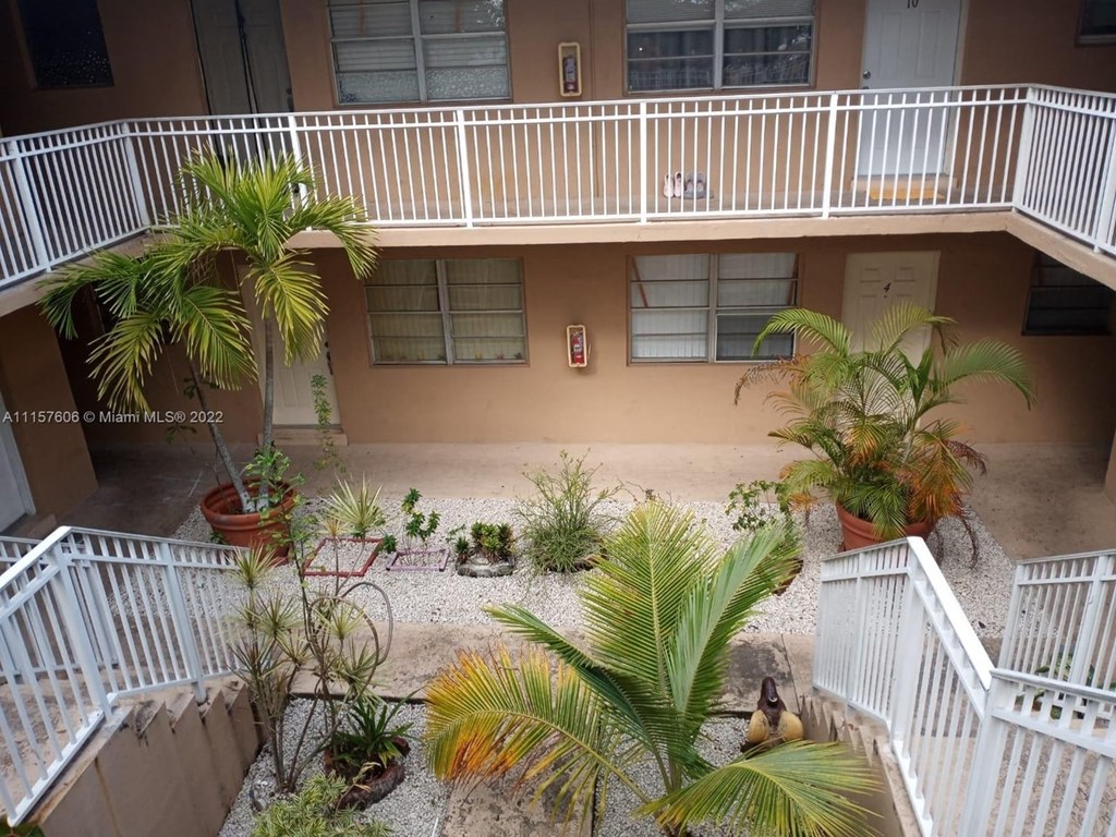 an aerial view of a building with a balcony and palm trees