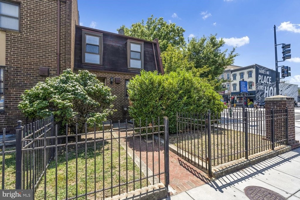 the front yard of a brick house behind a metal fence