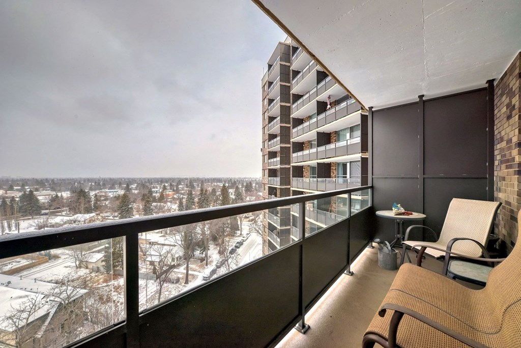 a balcony with two chairs and a view of a city in the snow