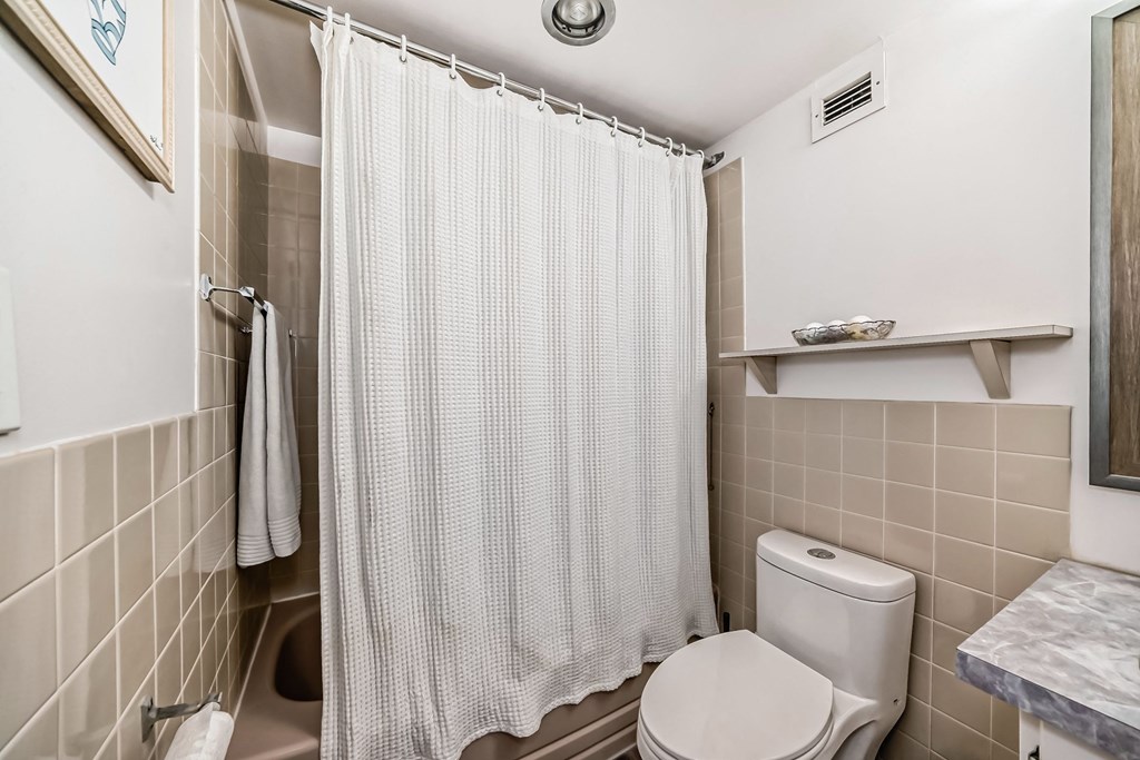 a bathroom with a shower and a toilet and a shower curtain