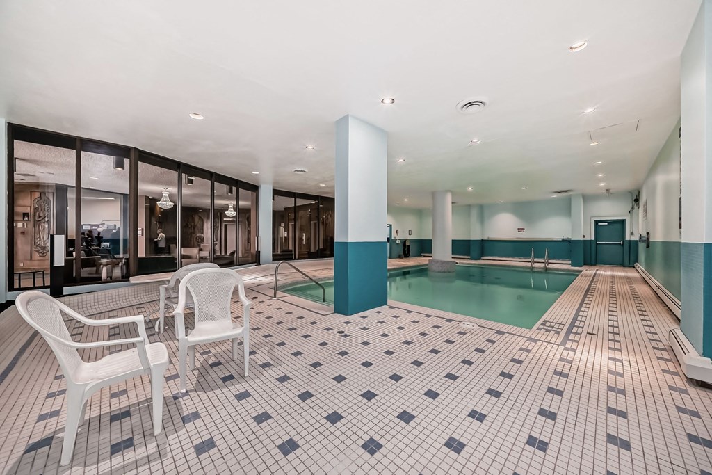 a large swimming pool with white chairs and a blue and white tiled floor