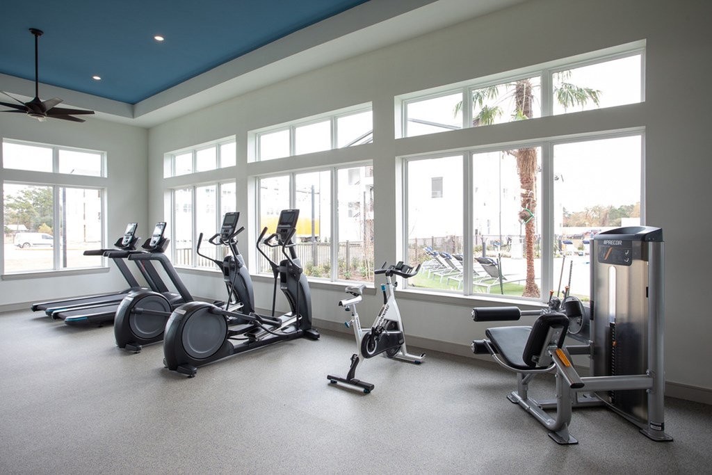 a gym with cardio machines and windows in a building
