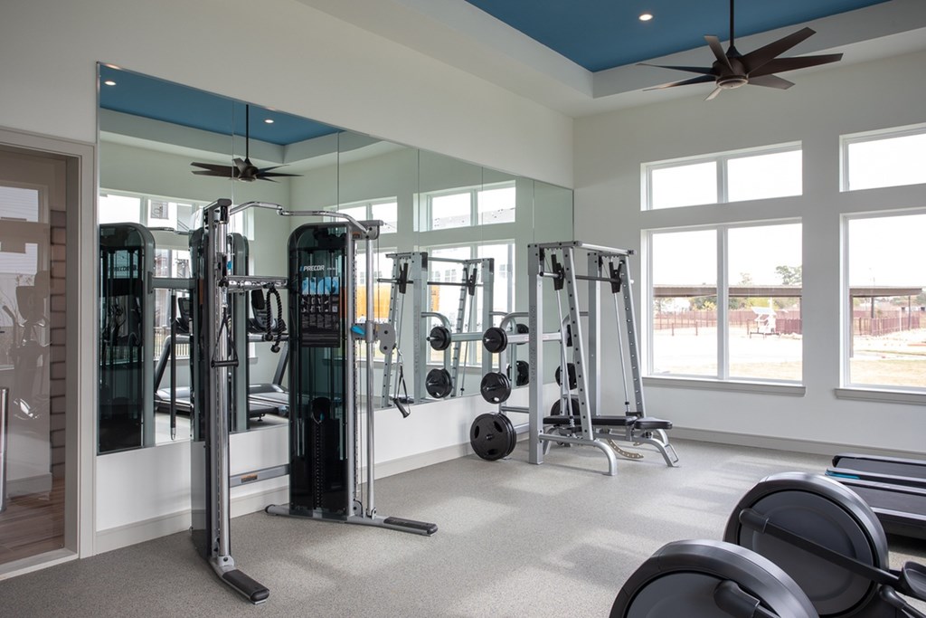 a fitness room with weights and mirrors and windows