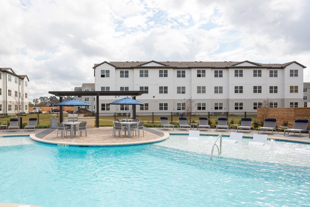 a swimming pool with chairs and umbrellas in front of a building