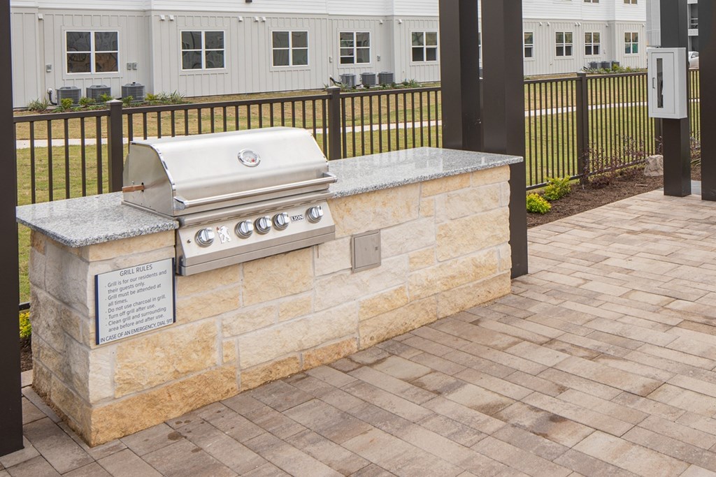a travertine outdoor grill area with a stone counter top on a patio