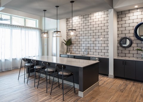 a kitchen with an island and chairs in front of a brick wall