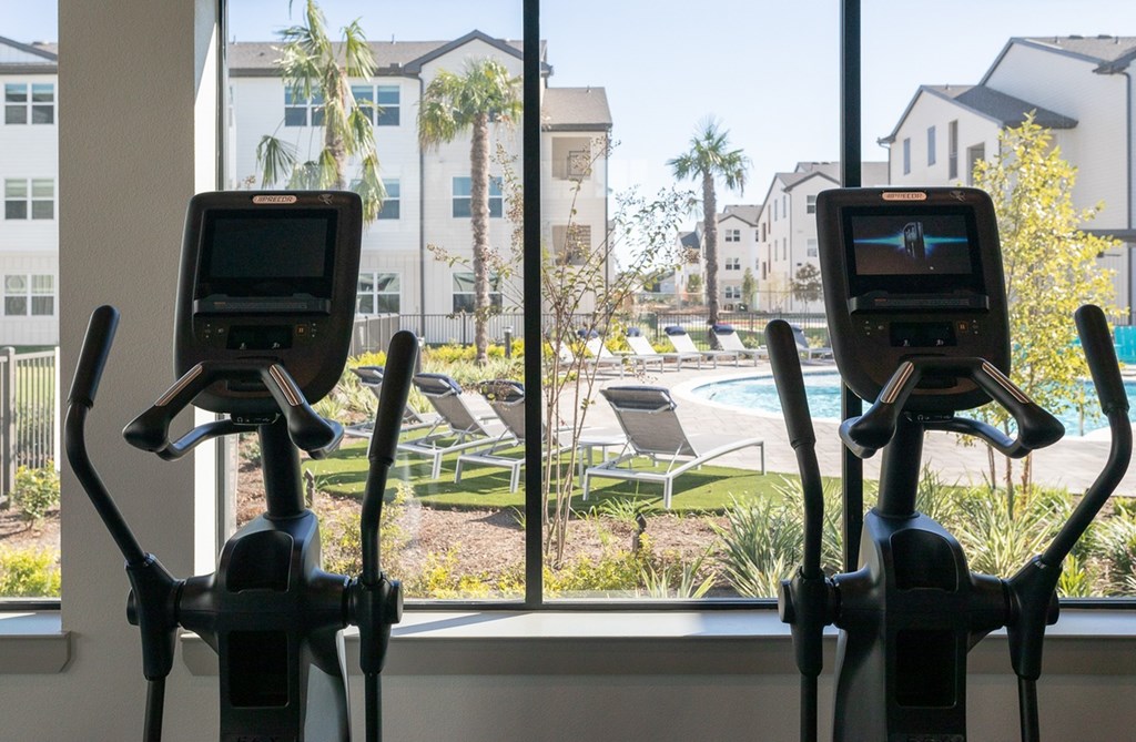 a gym with a view of a swimming pool and buildings