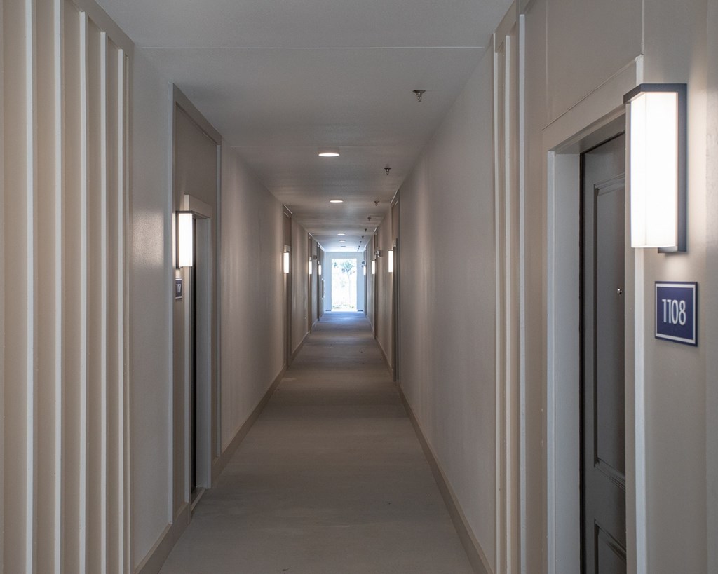 a long hallway with doors and a light at the end of it