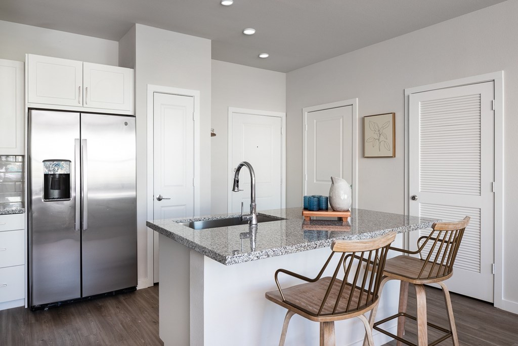 a kitchen with a marble counter top and a stainless steel refrigerator