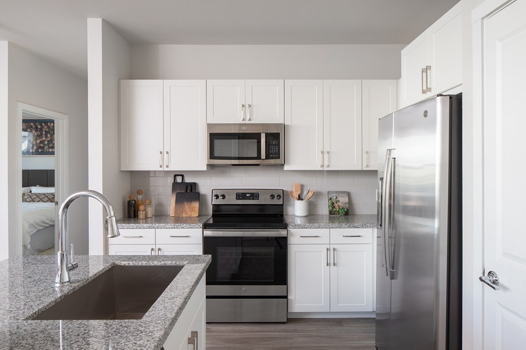 a white kitchen with stainless steel appliances and granite counter tops