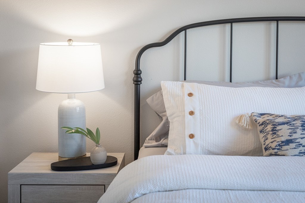 a bedroom with a bed and a nightstand with a lamp