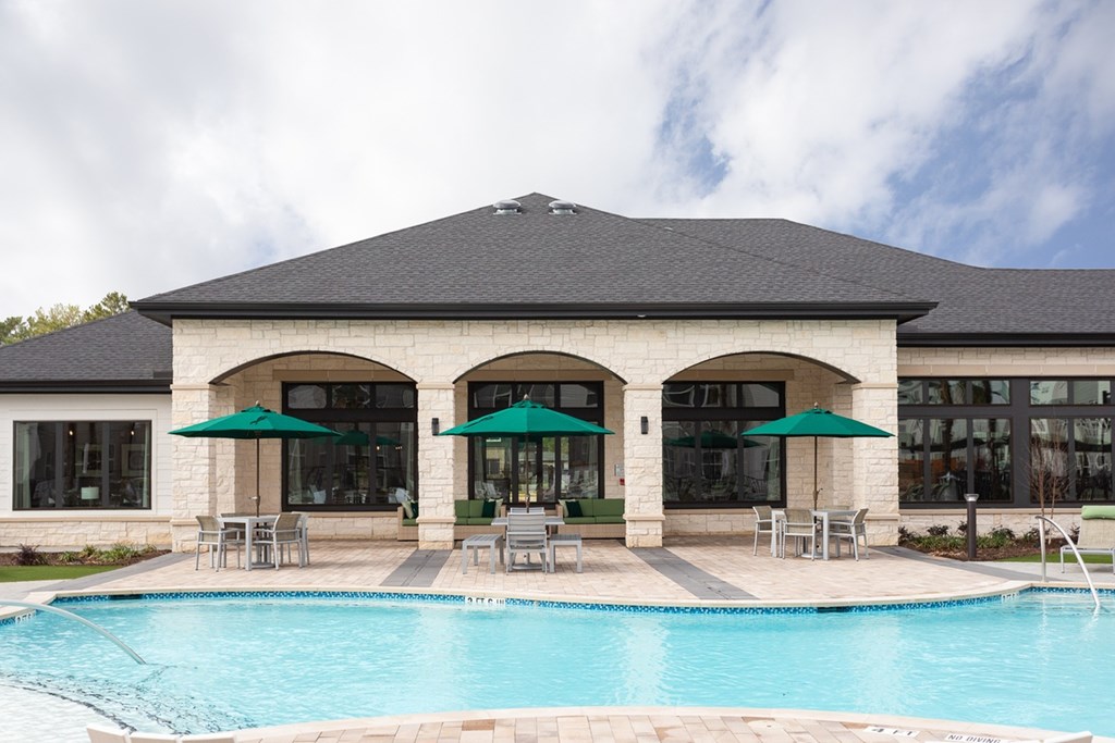 a swimming pool in front of a building with umbrellas
