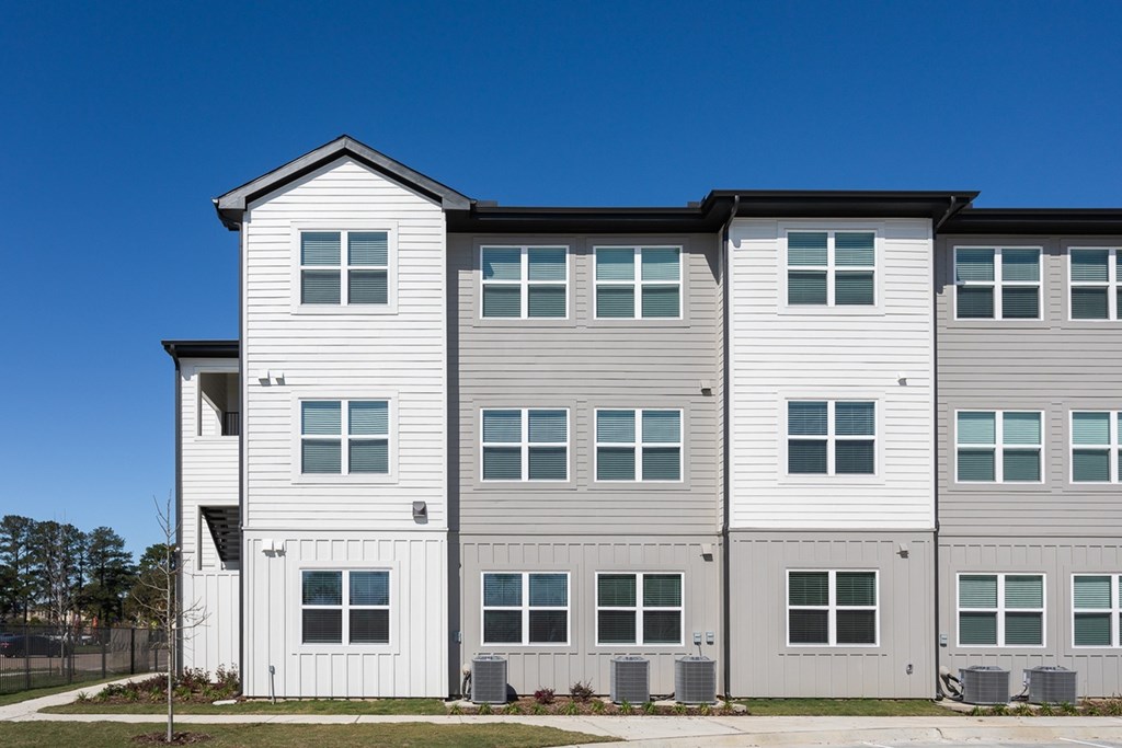 an apartment building with white siding and a blue sky