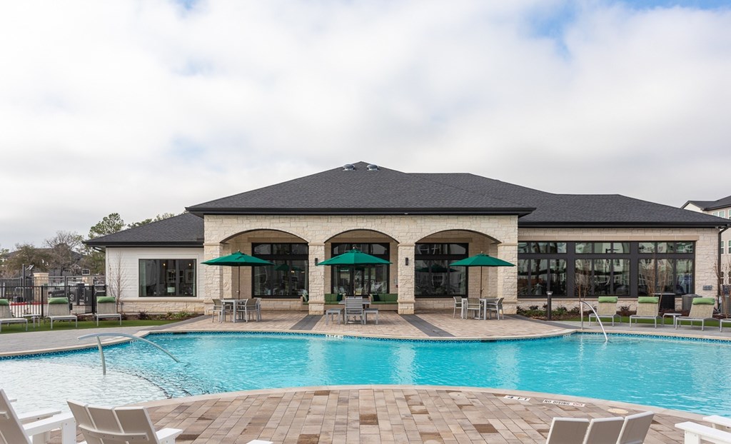 a swimming pool with chairs and umbrellas in front of a building