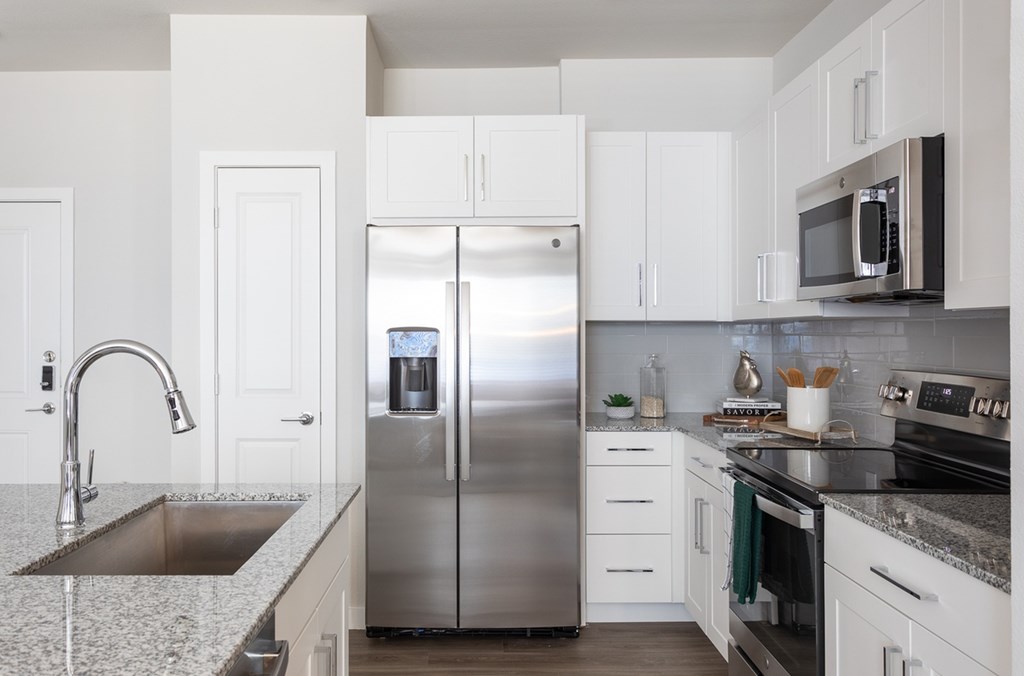 a modern kitchen with stainless steel appliances and white cabinets