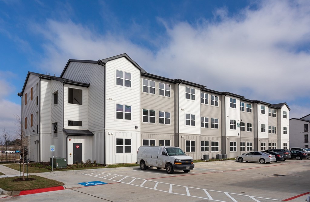 a large apartment building with a van parked in a parking lot