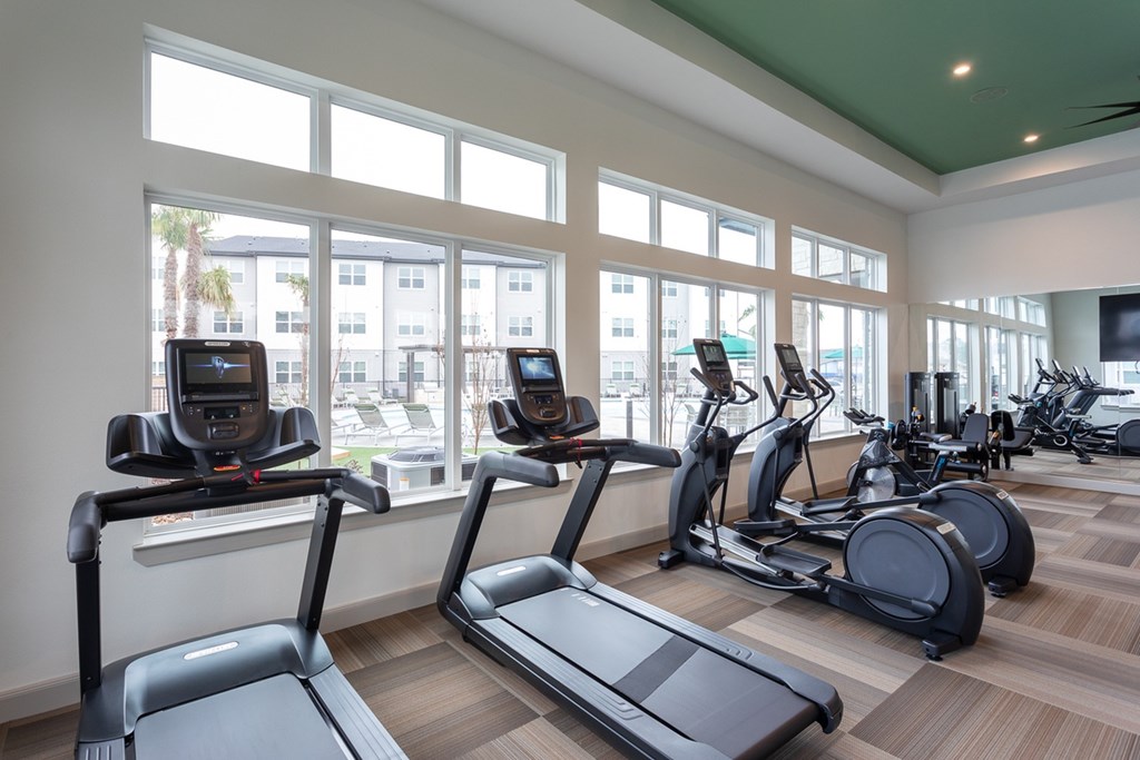 a gym with cardio equipment and windows in a building