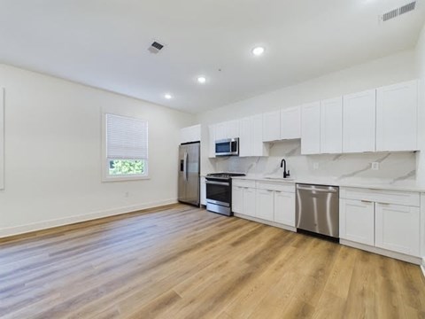 A kitchen with white cabinets and a wooden floor.