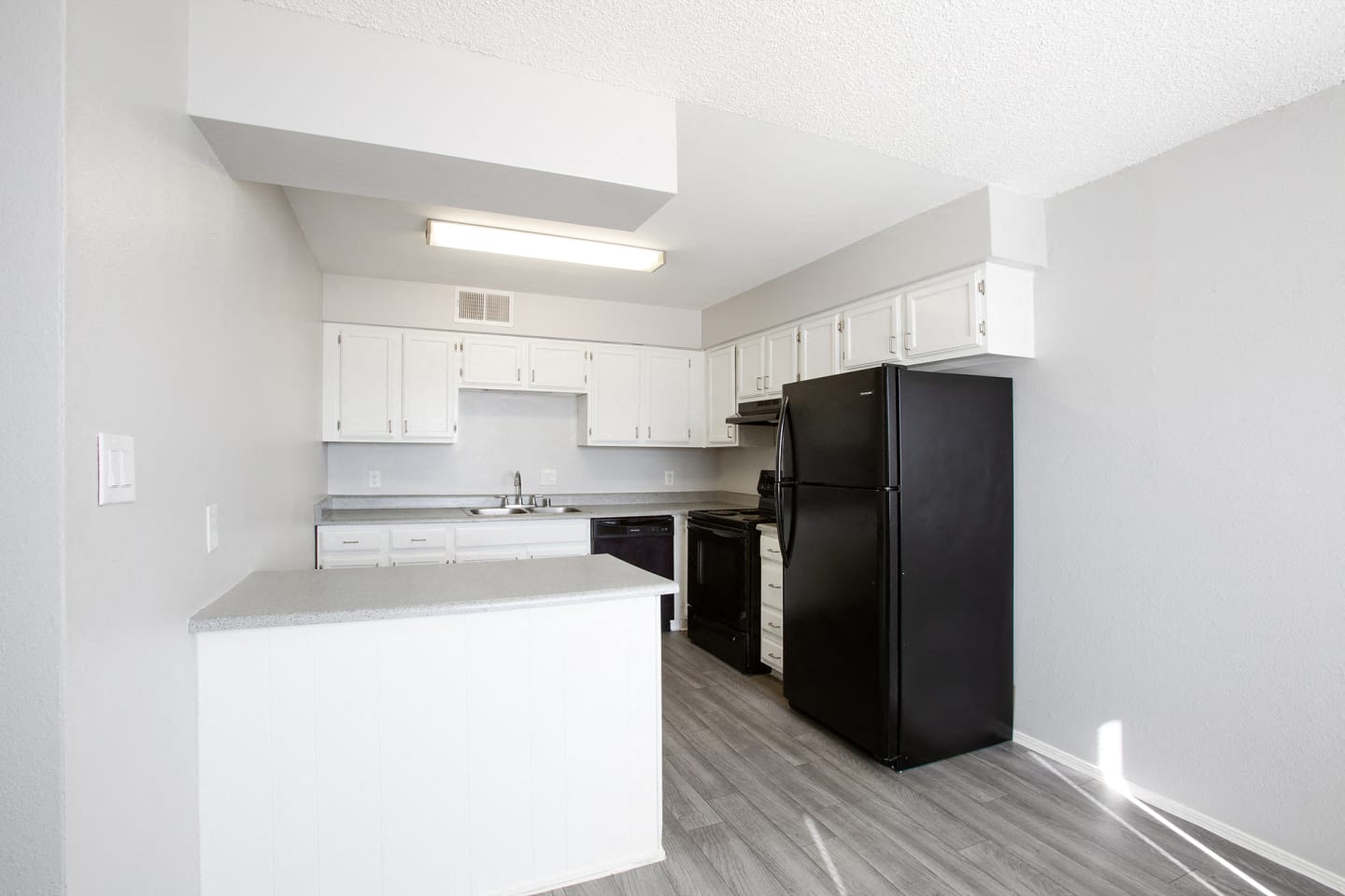 a kitchen with white cabinets and a black refrigerator