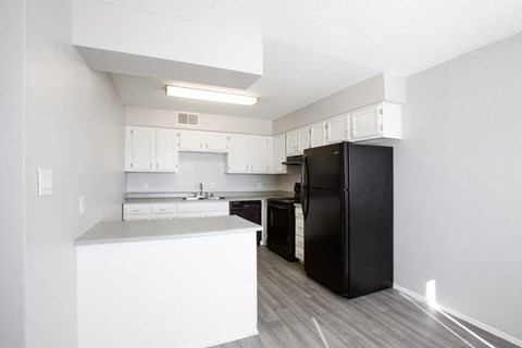 a kitchen with white cabinets and a black refrigerator