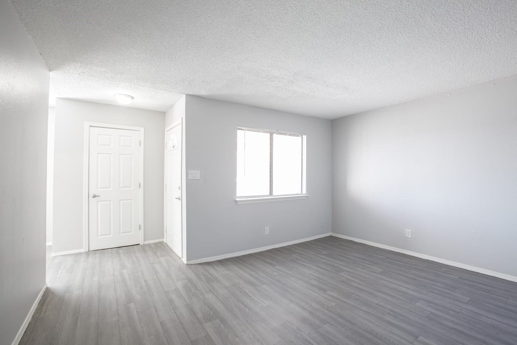 an empty living room with white walls and a window