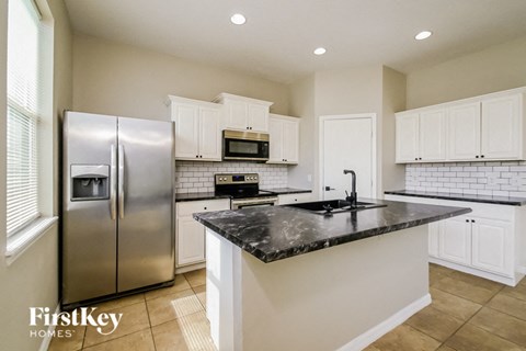 a kitchen with white cabinets and a black counter top