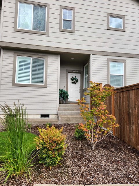 A house with a grey siding and a white door with a wreath on it.