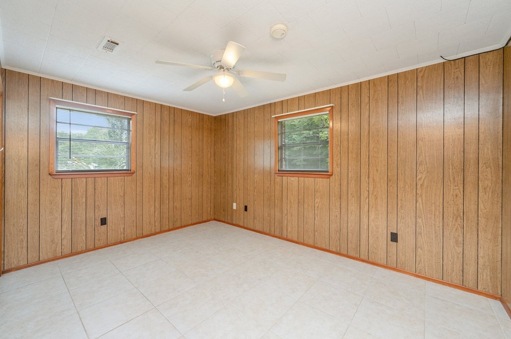 the living room has wood paneling and a ceiling fan