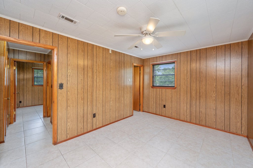 an empty room with wood paneling and a ceiling fan