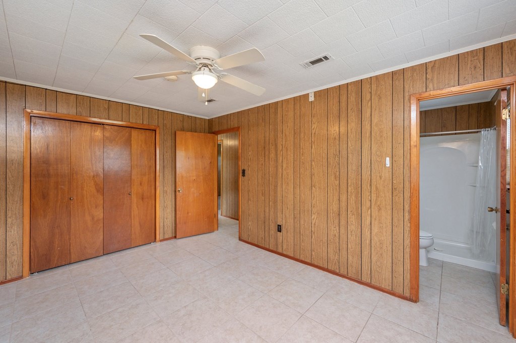 an empty living room with wooden walls and a ceiling fan