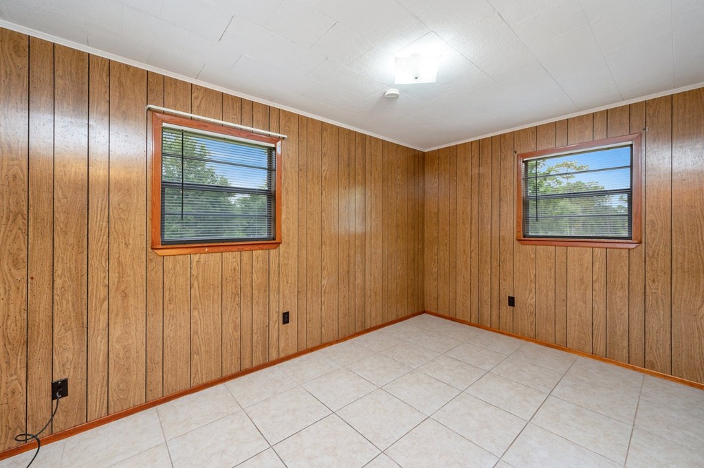 the living room of a house with wood paneling and a tiled floor